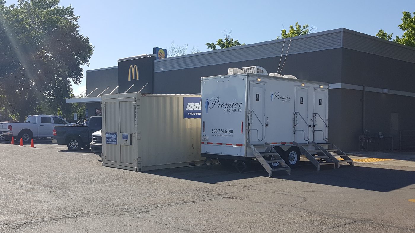 Restroom trailer on site at a fast-food franchise remodel, with the restaurant operating during construction