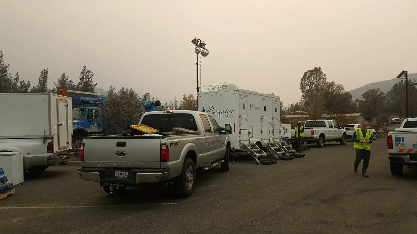 Restroom trailer at a public utility staging area with PG&E trucks and field crews