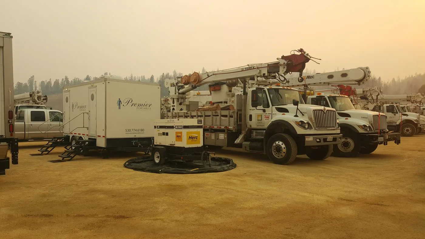 Restroom trailer deployed alongside emergency utility crews and bucket trucks during a disaster response