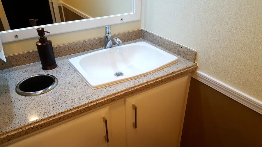 Granite countertop vanity with chrome faucet and soap dispenser inside a 3-station restroom trailer