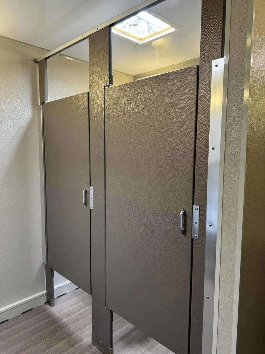 Private restroom stalls with full-height doors and hardware inside a restroom trailer