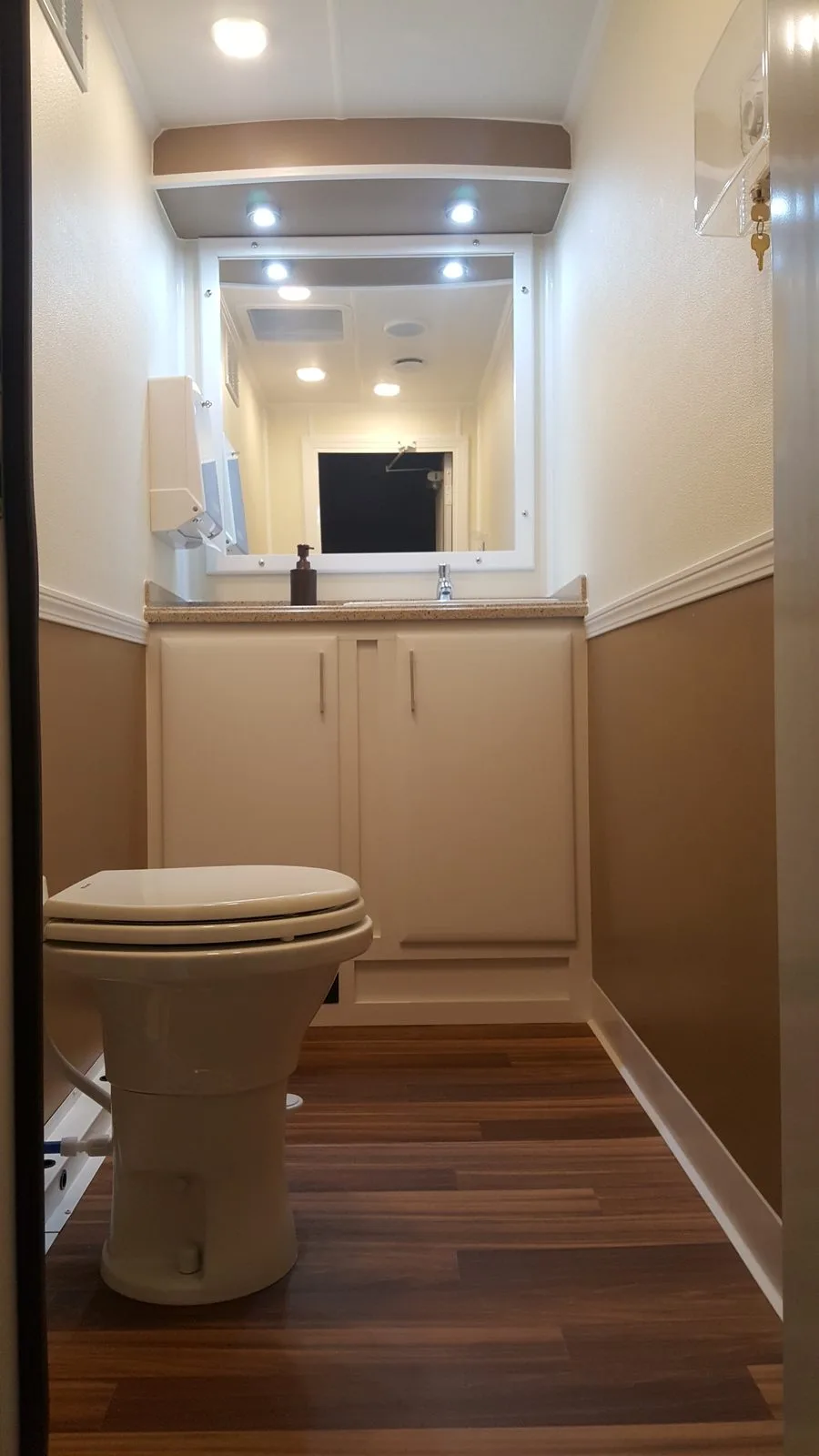 Interior of women's restroom station in the 3-station trailer showing toilet, vanity, recessed lighting, hardwood floor and climate control