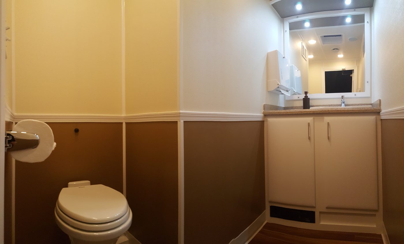 Interior of the 3-station restroom trailer showing vanity, mirror, recessed lighting and hardwood floor
