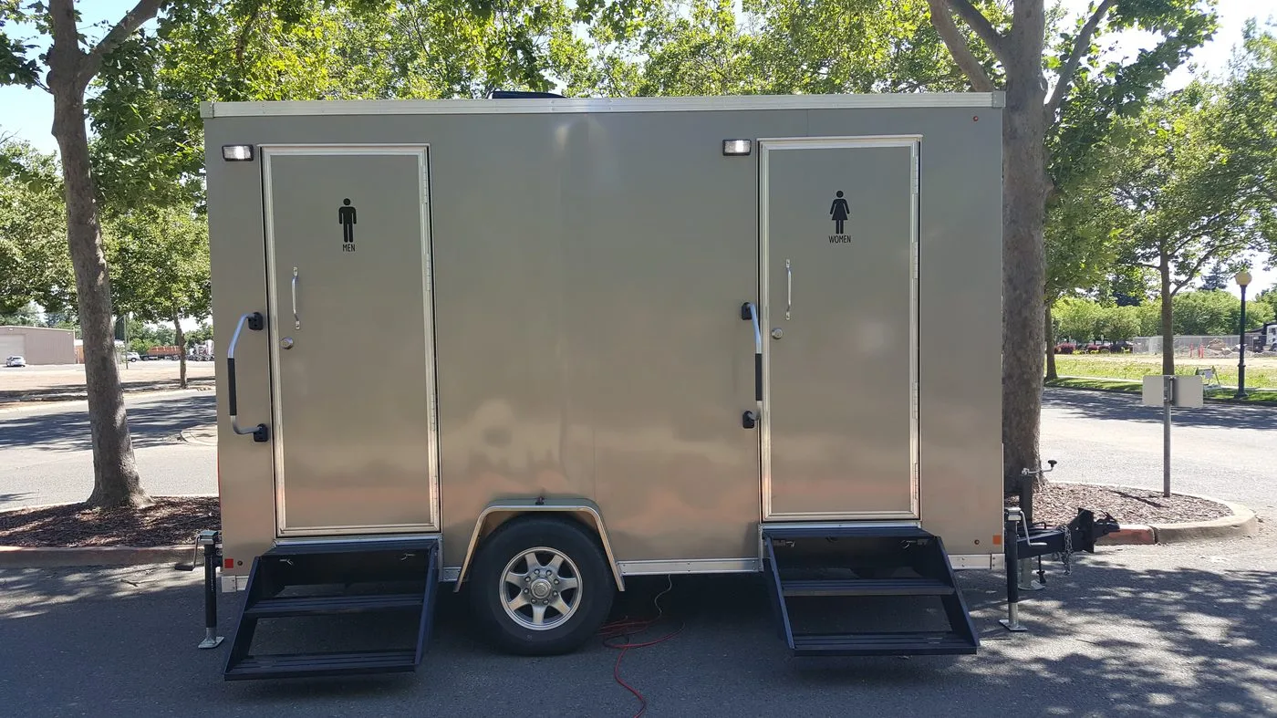 Clean restroom trailer with men's and women's entrances staged and ready for deployment