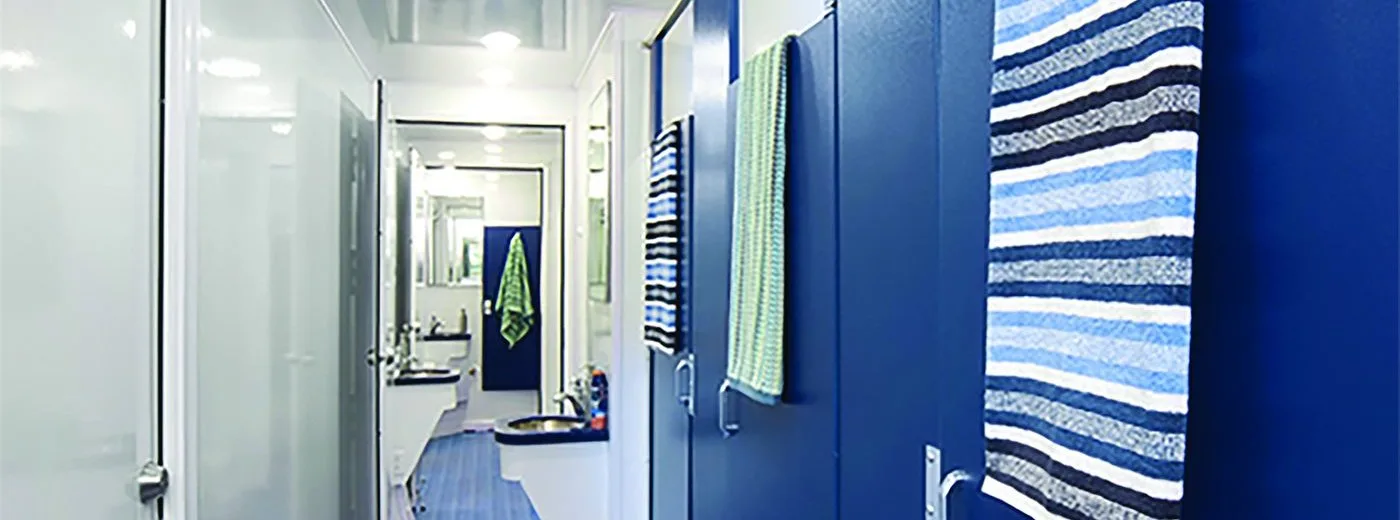 Interior hallway of an 8-station Satellite Suites Flex shower trailer with private locking stall doors and recessed lighting