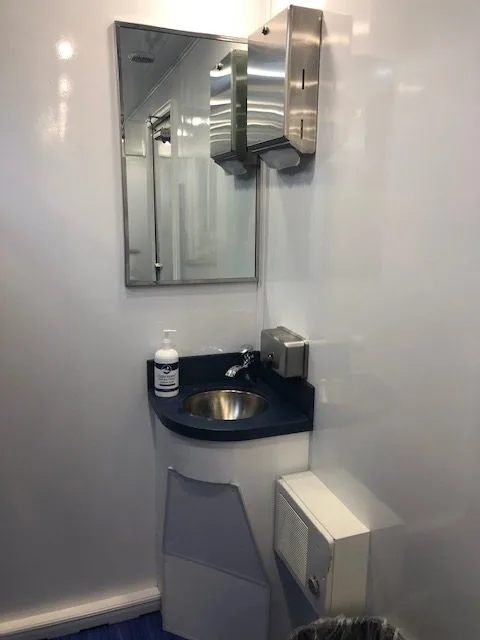 Stainless sink, mirror, soap dispenser, and paper towel dispenser inside the shower trailer