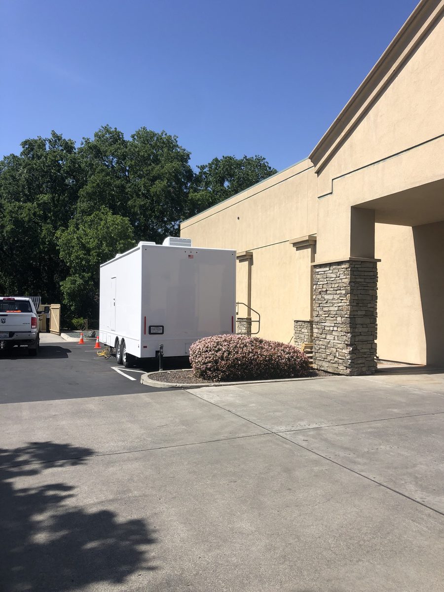 Restroom trailer positioned next to a commercial office building entrance during a bathroom remodel, Sacramento region