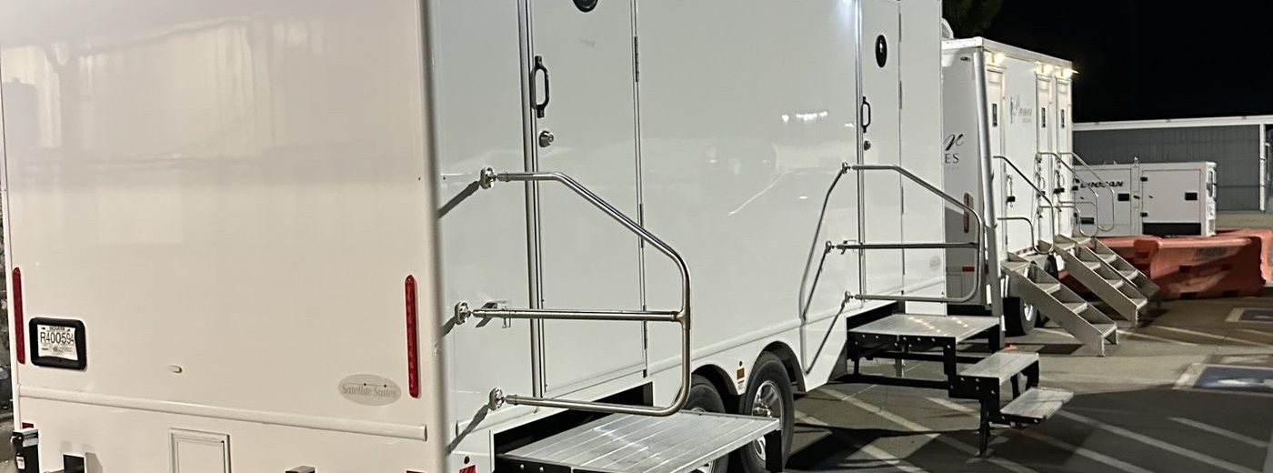 Row of restroom trailers staged at night at a Sacramento-region distribution center