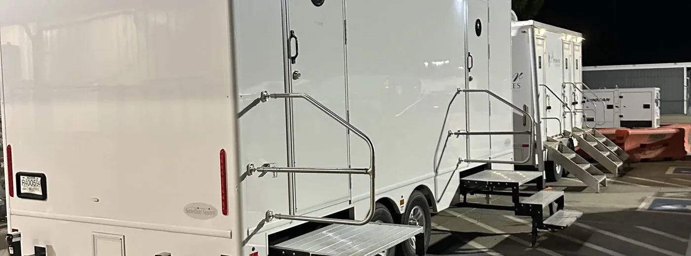 Row of restroom trailers staged at night at a Sacramento-region distribution center