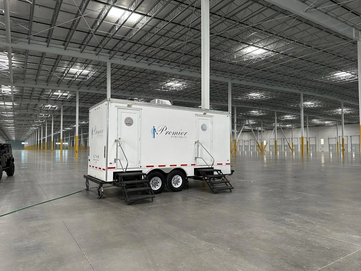 Restroom trailer positioned inside a large empty distribution warehouse during commercial construction